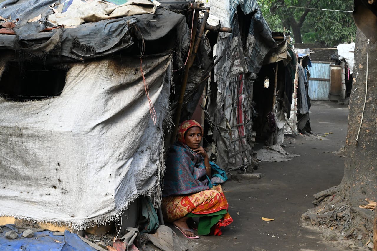 about-us A woman sits outside a temporary shelter in a slum area of Chittagong, Bangladesh.